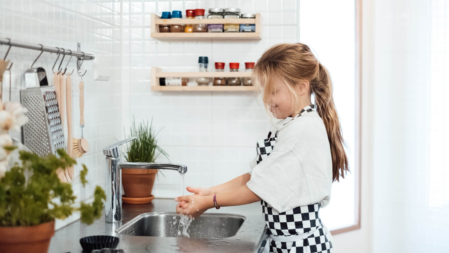 Een meisje op de buitenschoolse opvang van Kindergarden wast haar handen in de BSO Keuken.