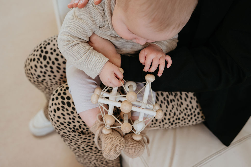 baby speelt op schoot bij pedagogisch medewerker